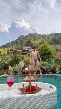 Handsome male model relaxing happily by the outdoor swimming pool in summer.