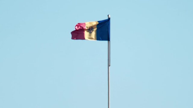 Moldovan flag waves proudly against clear blue sky dynamic motion patriotism.