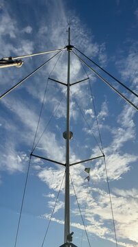 A Parasailer Drifts Near a Boat Mast Under a Cloudy Sky - Low Angle Shot