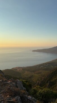 A Stunning Sunset Glows Over the Sea and Rocky Cliffs in Buggerru, Sardegna, Italy - Vertical Shot