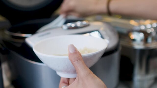 Close Up of Person Serving Steamed Rice into a White Bowl