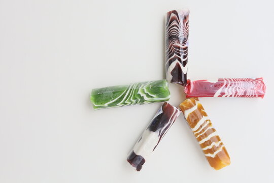 Five pieces of Dodol Garut, traditional Indonesian sweet taffy, with colorful striped patterns in red, green, and brown, isolated on a white background.
