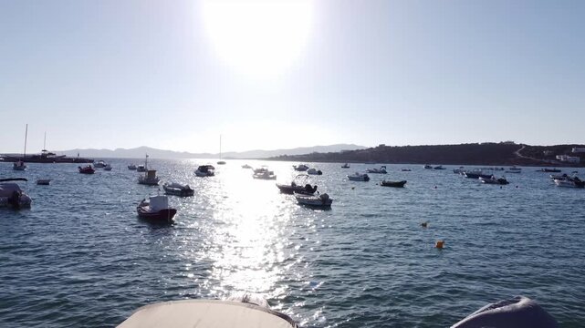 Fishing boats moored in aegean sea, sunlight reflection and shimmering effect in sea water, Paros port on greek island, Drone shot