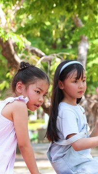 Two Young Thai Sisters Playing Together in a Sunny Public Park