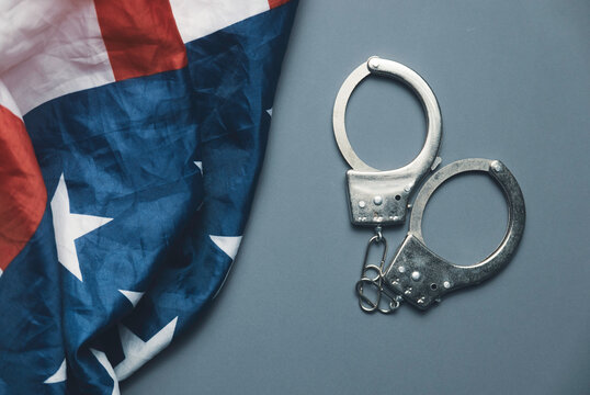 Metal Handcuffs Next to United States Flag Representing Law Enforcement and Criminal Justice System in America