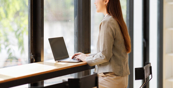 Asian woman working on laptop at standing desk