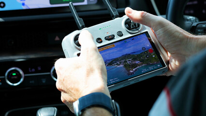 Hands Operating a Drone Remote Controller Inside a Vehicle in Phuket © blueringmedia