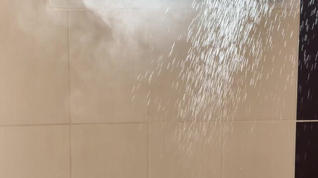 Hot Water Spraying Against Beige Bathroom Tiles with Thick Steam