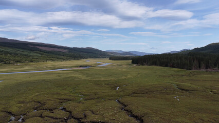 Obraz premium Aerial View of a Winding River Through Scottish Highland Valley