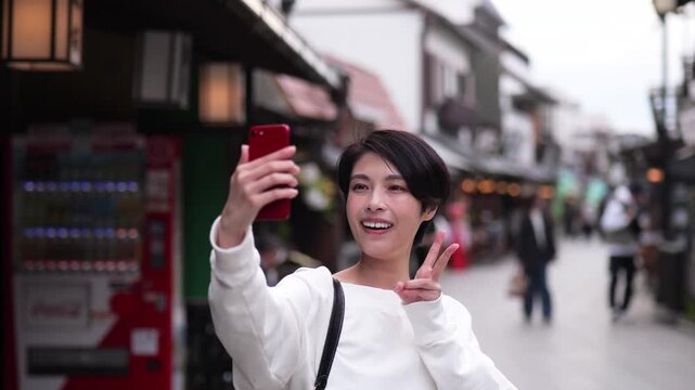 観光地でスマートフォンで自撮りをする女性