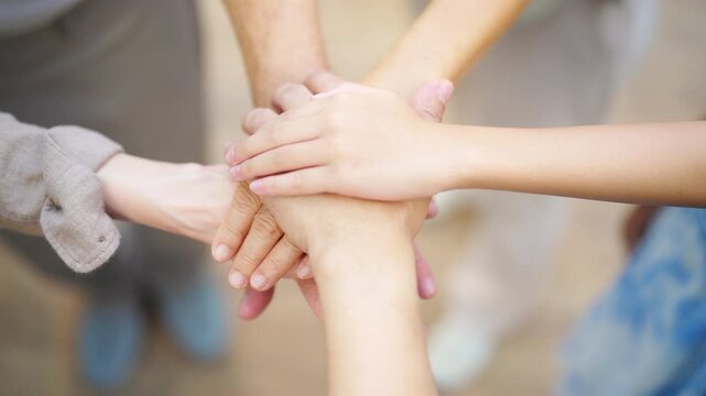 Close up of Asian multi-generation family hands stacked together. Grandparents, parents and child showing unity support and teamwork, family bonding gesture during happy relationship connection