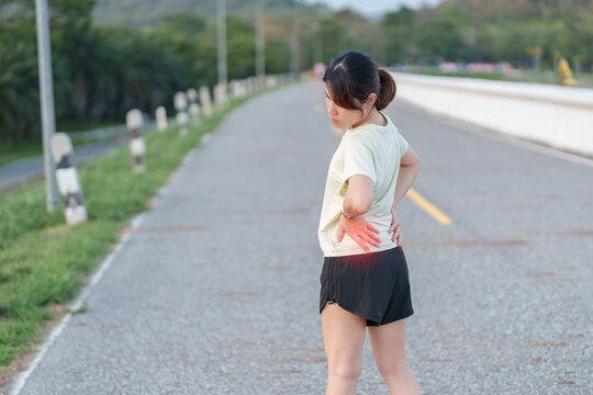 Adult female runner with back and waist ache due to piriformis syndrome and low back pain. Woman having muscle injury or spinal compression during running. Sports medicine and healthcare concept