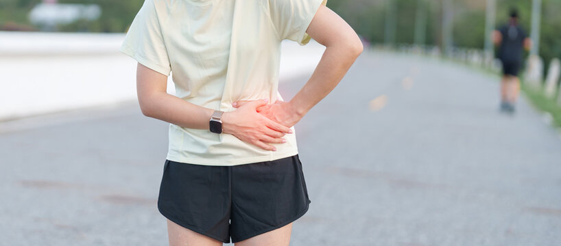 Adult runner suffering from side stitch and waist pain during exercise. woman holding his side due to sharp abdominal cramp or muscle ache while running. Sports injury and healthcare concept