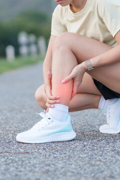 Young adult woman runner suffering from acute calf muscle pull and leg ache during running workout. female athlete holding his painful leg due to sports injuries. Medical and healthcare concept