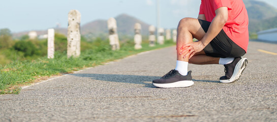 Young adult man runner suffering from acute calf muscle pull and leg ache during running workout. Male athlete holding his painful leg due to sports injuries. Medical and healthcare concept © Jo Panuwat D