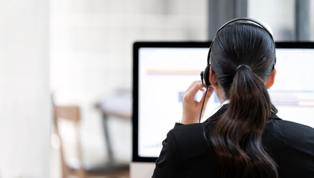 Rear view of female call center agent working with headset in office