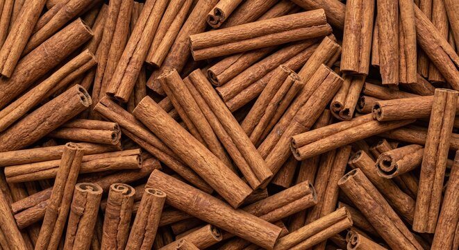 A rich, overhead arrangement of dried cinnamon sticks, showcasing their warm brown hues and textured surfaces, baking, beverages, and aromatic use