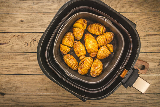 Golden crispy potatoes are being air fried in a modern black air fryer