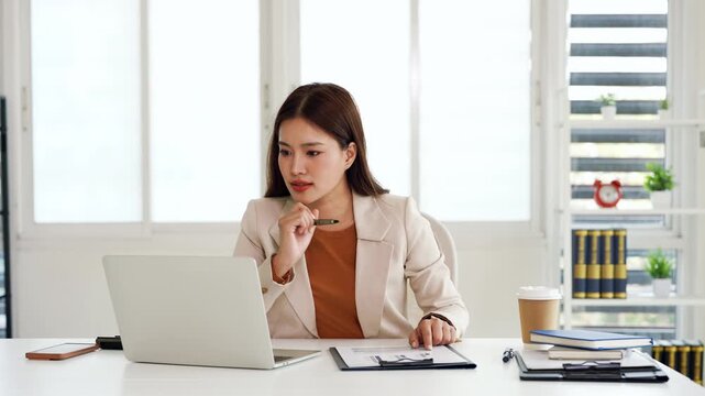 Young business woman doing finance, review  paper document and typing on laptop.