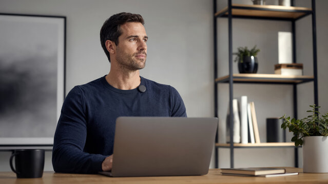 Athletic man using smart bio-sensor for ergonomic posture while working at computer