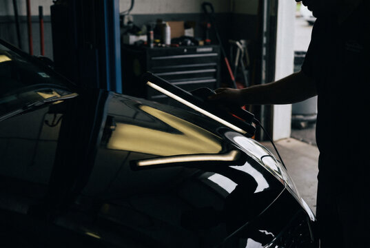 Paintless dent repair PDR glue pulling tabs adhered to dark car body panel for dent extraction body repair process