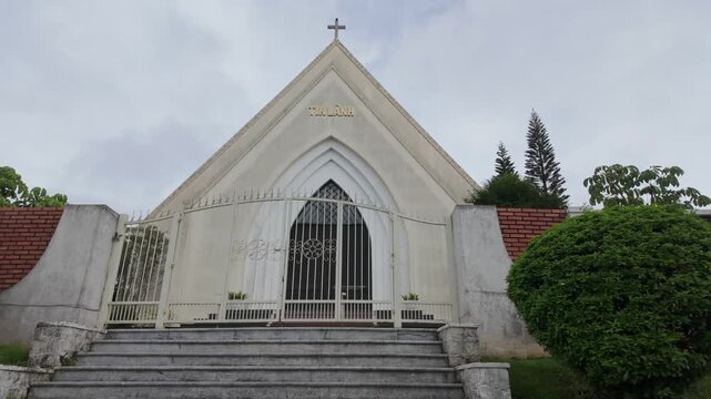 A Protestant church with the words "Tin L&agrave;nh" meaning Protestant in Vietnamese, located in Da Lat, Vietnam. The church features a prominent cross on its roof and a decorative gate.