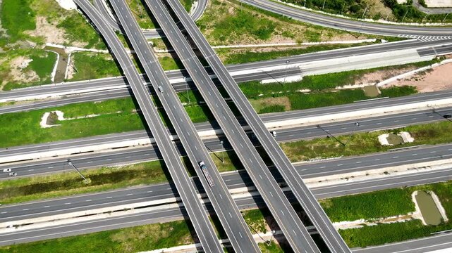 Aerial view of modern highway interchange with multilayer roads and curved ramps surrounded by green farmland, showcasing transportation infrastructure, urban development, and road network planning.