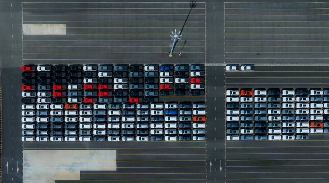 Aerial drone view of thousands of new cars parked at port for global export.