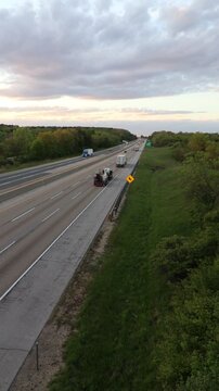 Vertical video of cars and semi trucks drive down a long interstate highway road into the horizon in the top right third of the screen.