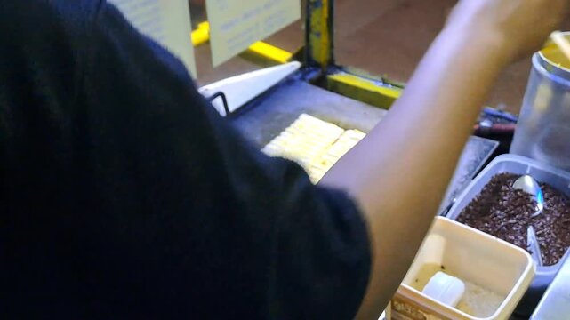 Close-up of a street food vendor preparing authentic Indonesian sweet martabak (Terang Bulan) and grilled toast (Roti Bakar). The footage showcases the detailed process of pouring batter, give butter.
