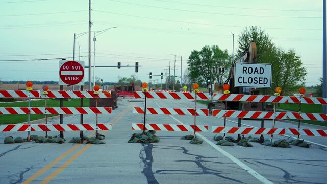 Blocked roadway with barricades and warning sign ROAD CLOSED and STOP at dusk showing restricted access and construction area. Front view
