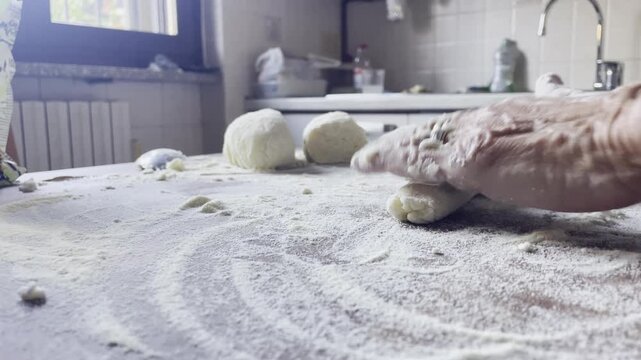 Close Up of Artisan Hands Rolling Fresh Gnocchi Dough on Floured Wooden Table