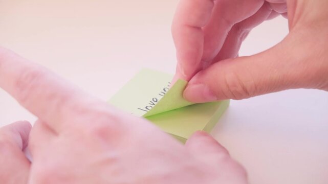 The process of peeling off the sticker with the love message I love you on a light surface. Video footage of tender feelings.