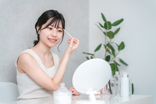 Young Asian woman doing her makeup at home (eyebrows, makeup)