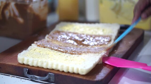 Toast seller's hand puts milk and sprinkles ceres on toast for his customer	