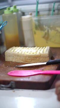 Toast seller's hand puts milk and sprinkles ceres on toast for his customer	