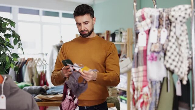 Young man buyer scanning qr code for women's lace lingerie in clothing store