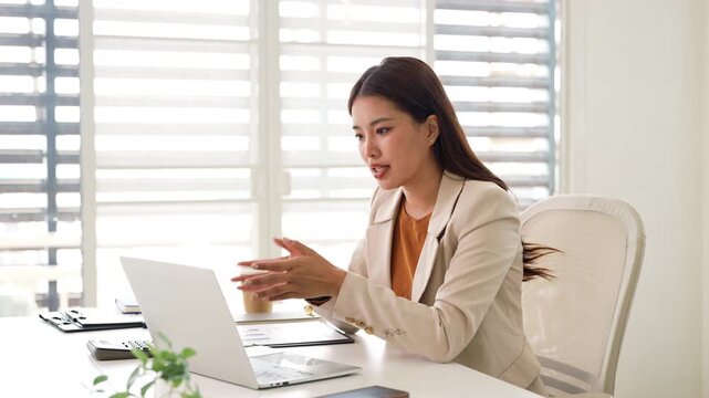 Confident young businesswoman  discussing project details with clients on video call. Skilled woman worker conducting online meeting with colleagues.