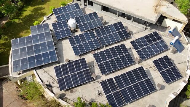 An aerial view of a modern rooftop solar power system installed on a large building. Multiple photovoltaic solar panels are arranged efficiently across the rooftop to generate clean, renewable energy.