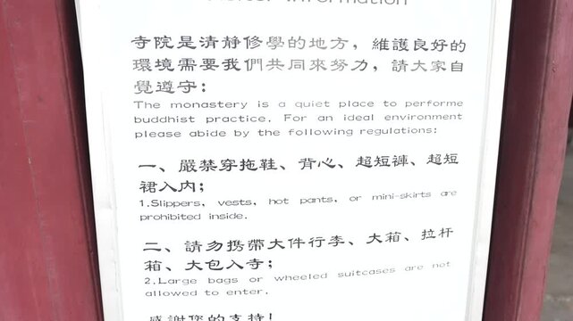 Close up of a bilingual visitor information sign with regulations for entering a Buddhist temple