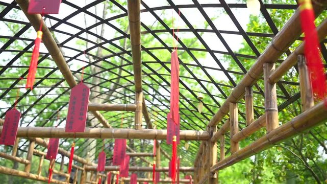 Red ema wishing plaques with prayers hanging from a bamboo tunnel in a garden in Suzhou, China
