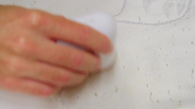 Hand holding a fabric shaver, removing lint and pilling from a fabric garment, extending its lifespan and maintaining appearance.