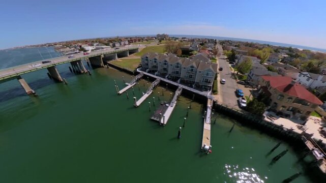 An FPV drone point of view over the Atlantic Beach Bridge on a sunny day. The camera dolly in, pan right and tilt down flying over the bridge. Vehicles and the blue sky is visible.