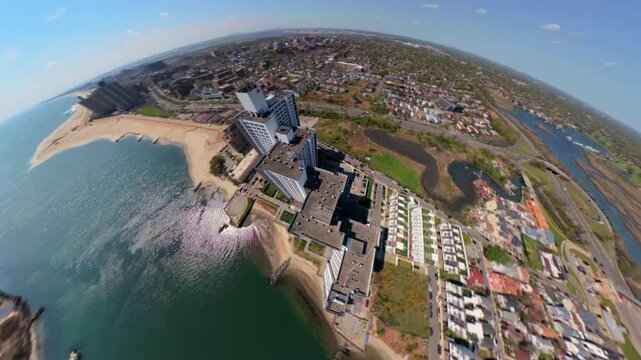 An FPV drone view over Reynolds Channel by the Sand Castle Oceanfront Living apartments on a sunny day. The camera tilted down, boom down and orbit around the buildings by the Atlantic Beach Bridge.