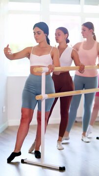 Group of enthusiastic young female ballet students focused on mastering graceful Demi rond de jambe par terre exercise at barre in mirrored well-lit choreography studio. High quality 4k footage