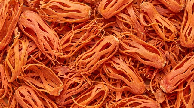 A vibrant close-up macro view of dried mace spice showcasing its intricate, fiery orange threads and delicate fibrous texture creating a visually rich and aromatic culinary background