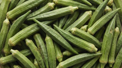 Fototapeta premium Abundant pile of fresh green okra pods with ribbed texture and pointed ends filling the frame ladyfinger