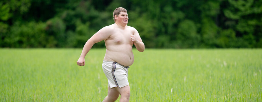 Jogging man crosses grass field. Overweight jogging shows effort. Beginner jogging fitness concept. Jogging supports healthy change.