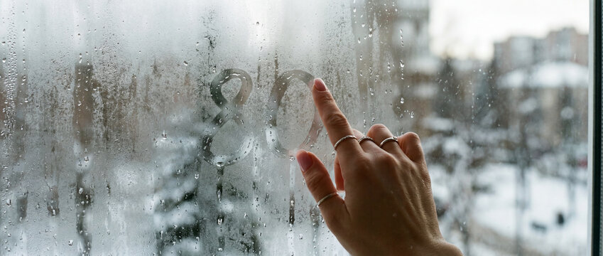 Hand drawing number on steamy window looking outside