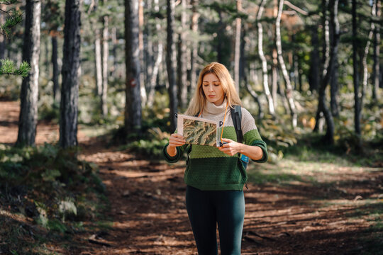 Woman navigating forest using a map and compass